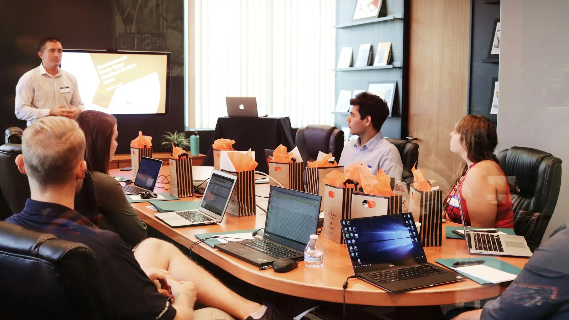 man standing in front of people sitting beside table with laptop computers